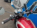 a red motorcycle parked in front of a blue and white bus