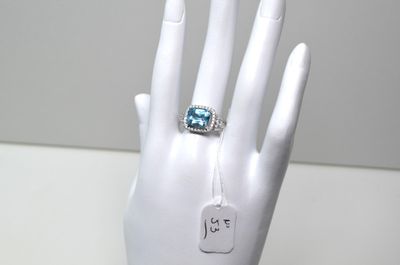 une main de mannequin blanche ornée d'une bague bleue
