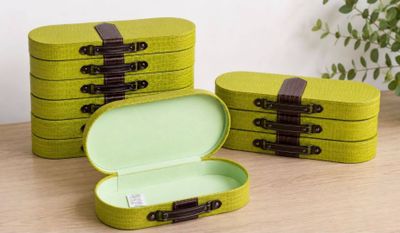 three green boxes with brown handles sitting on top of a wooden table