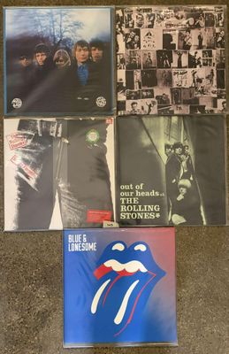 the rolling stones albums are sitting on a carpeted floor
