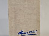 an old book with a blue logo on it sitting on a white surface
