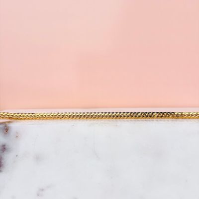un gros plan d'un collier plaqué or posé sur une surface en marbre