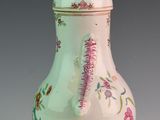 a white vase with pink flowers on it on a table