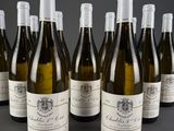 six bottles of white wine lined up in a row on a table