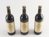 three bottles of wine sitting next to each other on a white surface