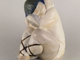 figurine représentant un homme assis par terre avec un sac d'argent