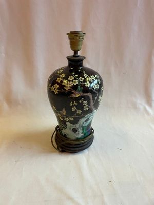 un vase noir et doré posé sur un socle, sur fond blanc