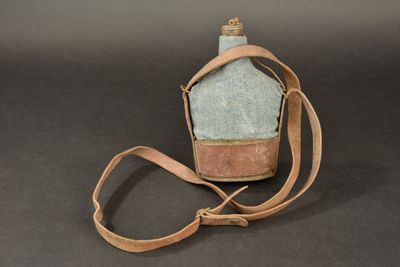 a blue bottle with a brown strap on a black background