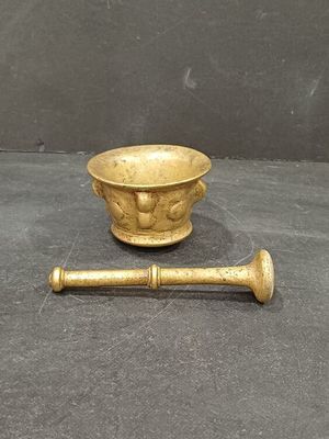 a small brass bowl and a wooden stick on the floor