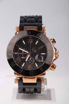 une montre noire et dorée exposée sur une surface blanche