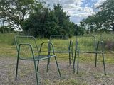 three green chairs sitting in the middle of a gravel field