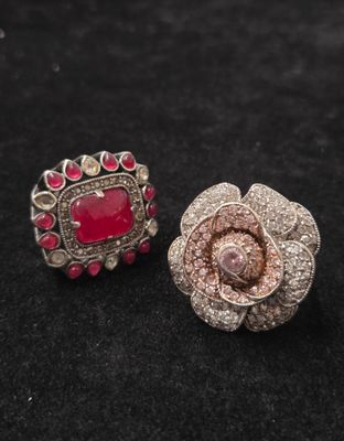 une paire de boucles d'oreilles roses et argentées posées sur une surface noire