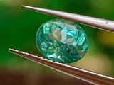 un gros plan d'un diamant vert tenu par une pince