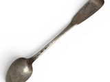 an old spoon with a metal handle sitting on top of a white surface