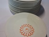 several white plates with orange designs on them sitting on a table