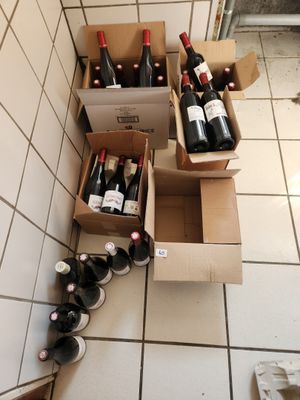 Des cartons de vin sont alignés sur le carrelage d'une cuisine