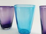 three different colored glasses sitting next to each other on a table