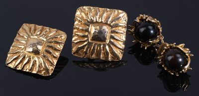 deux paires de boucles d'oreilles plaquées or, ornées de pierres noires sur un fond noir