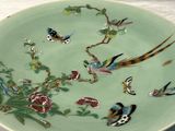 une assiette décorée d'oiseaux et de fleurs, posée sur une table