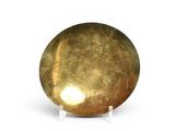 une boule dorée posée sur un socle, sur une surface blanche