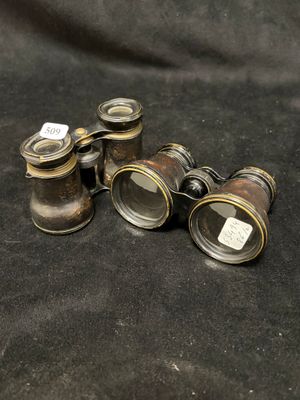 three antique binoculars are sitting on a black cloth