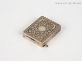 un petit livre argenté posé sur une surface blanche