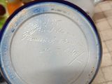 a person holding a blue and white plate with writing on it