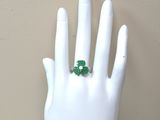 une main blanche portant une bague verte au doigt
