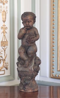une statue représentant un bébé tenant des raisins sur une table