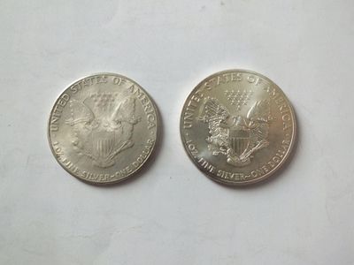 two silver coins sitting next to each other on a white surface