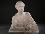 statue d'une femme assise sur un bloc de pierre, les mains posées sur les genoux