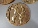 three gold medals with a picture of a man holding a baseball bat on one of them