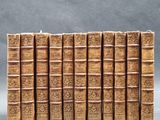 several old books are lined up in a row on a gray surface