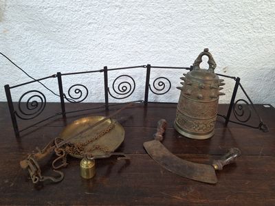 une table sur laquelle se trouvent une horloge, une cloche, un couteau et d'autres objets