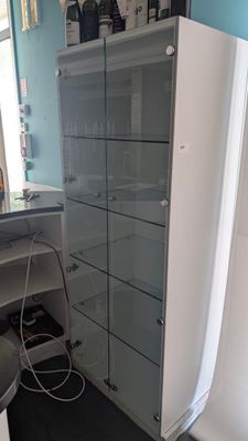 une armoire blanche à portes vitrées dans un coin de la pièce