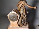 a statue of a woman holding a clock next to a clock on a table