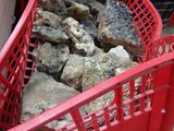 a red basket full of rocks on the ground