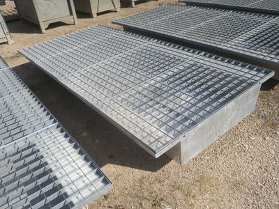 plusieurs grilles en acier sont empilées les unes sur les autres au sol
