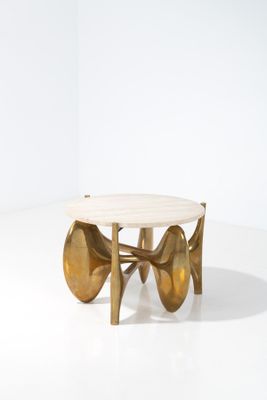 une table basse dorée avec un plateau en marbre sur un piètement blanc