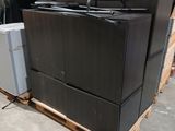 un tas d'appareils électroménagers noirs posés sur une palette dans un entrepôt