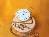 a pocket watch and a key on a piece of wood
