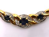 a close up of a gold necklace with sapphires and diamonds