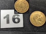 Trois pièces d'or sont posées sur un tissu noir, à côté d'une règle.