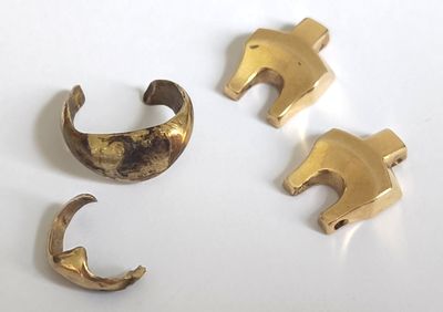 trois pièces en laiton sont représentées sur une surface blanche
