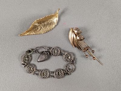 deux bijoux posés sur une table à côté d'une feuille