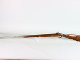 the rifle is laying on a white surface next to a ruler
