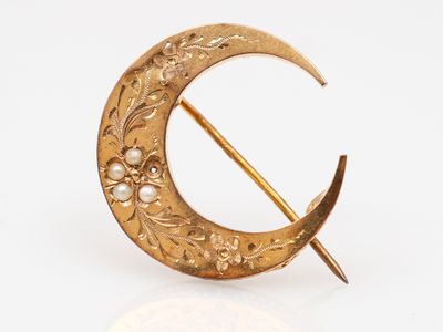 une image représentant une broche en or ornée de perles