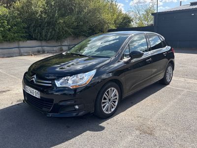 La voiture noire est garée sur un parking près d'un immeuble.
