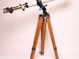 un vieux télescope posé sur un trépied, devant un fond blanc