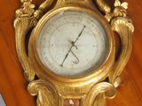 une horloge dorée posée sur un socle en bois accroché au mur